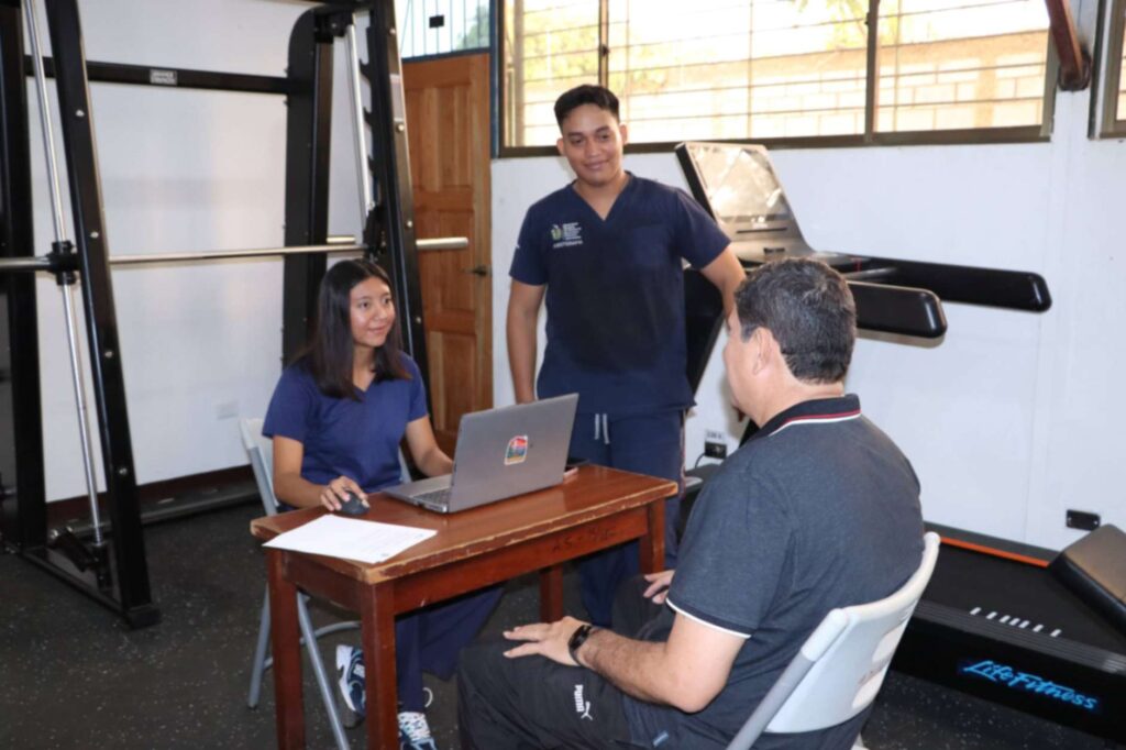 Estudiantes de Fisioterapia realizando evaluación ergonómica en el sector salud para mejorar el bienestar físico del personal.